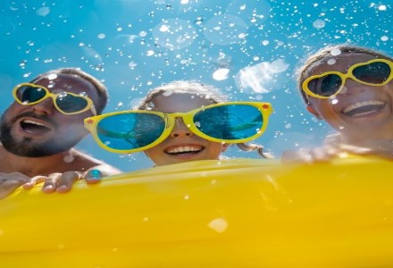 parents and child wearing sunglasses playing with water
